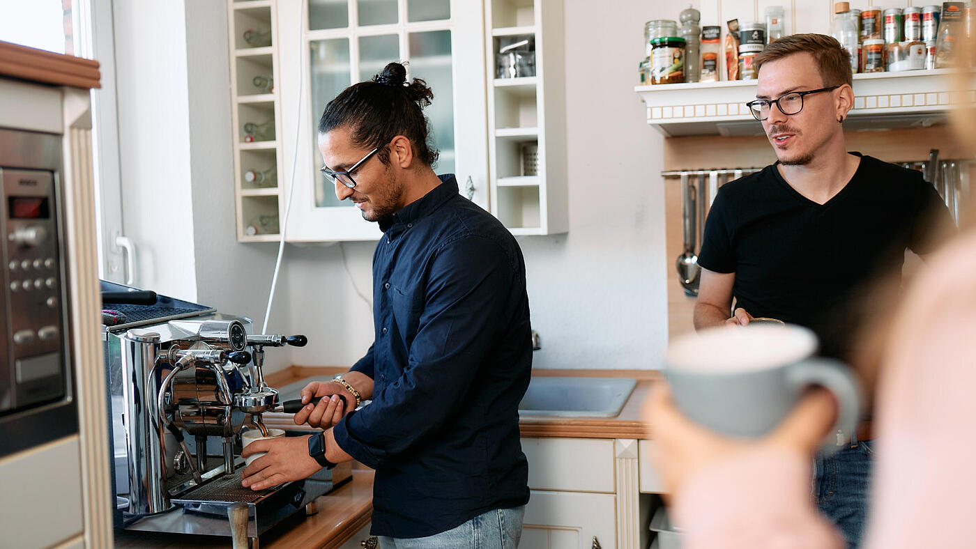 Mehrere Mitarbeitende von visuellverstehen holen sich in der modernen Küche einen Kaffee.