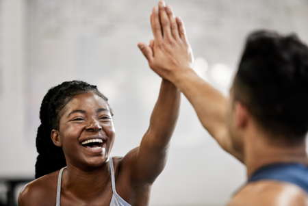 Eine Sportlerin und ein Sportler geben sich ein High Five.