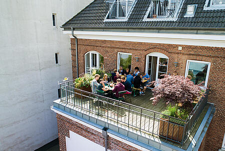 Der einladende Balkon der Werbeagentur visuellverstehen, auf dem Mitarbeitende zu Mittag essen.