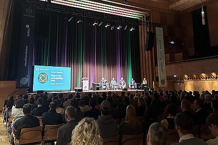 Podiumsgespräch mit fünf Personen im Deutschen Haus Flensburg zur OECONOMIA vor Publikum in einem bestuhlten Saal.