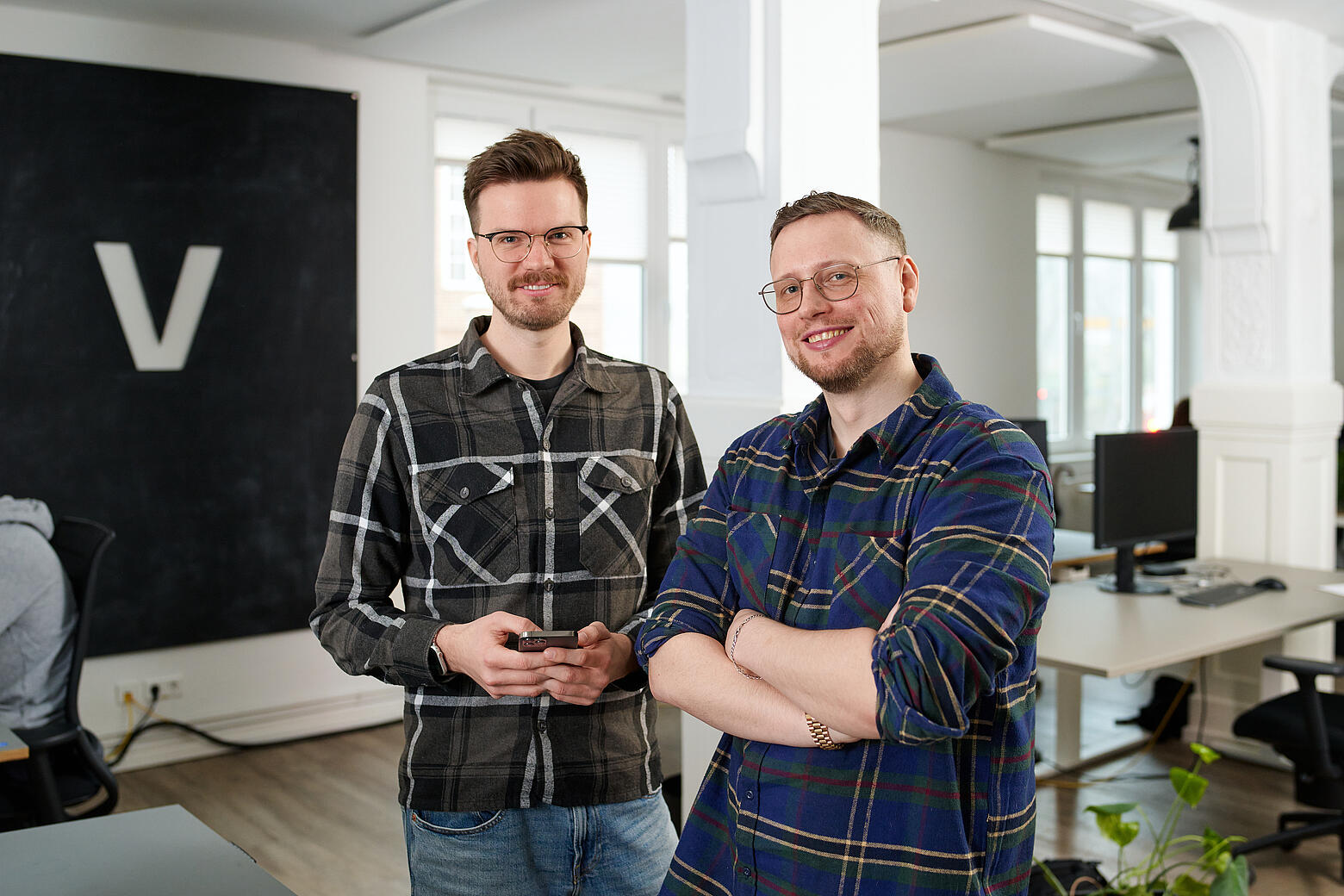 Lars und Per stehen nebeneinander in den Büroräumen von visuellverstehen.