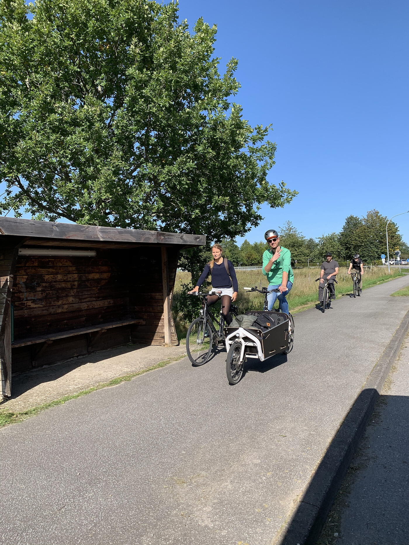 Zwei Mitarbeitende von visuellverstehen fahren Fahrrad, im Hintergrund Wiesen und blauer Himmel. 