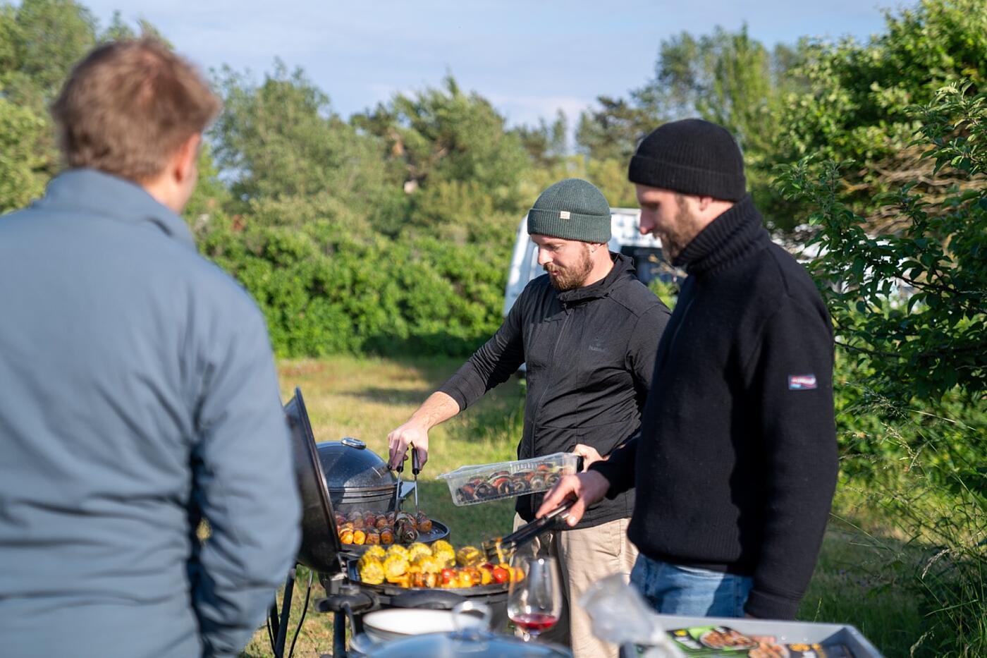 Drei Mitarbeiter von visuellverstehen stehen um einen Grill herum und wenden Spieße.