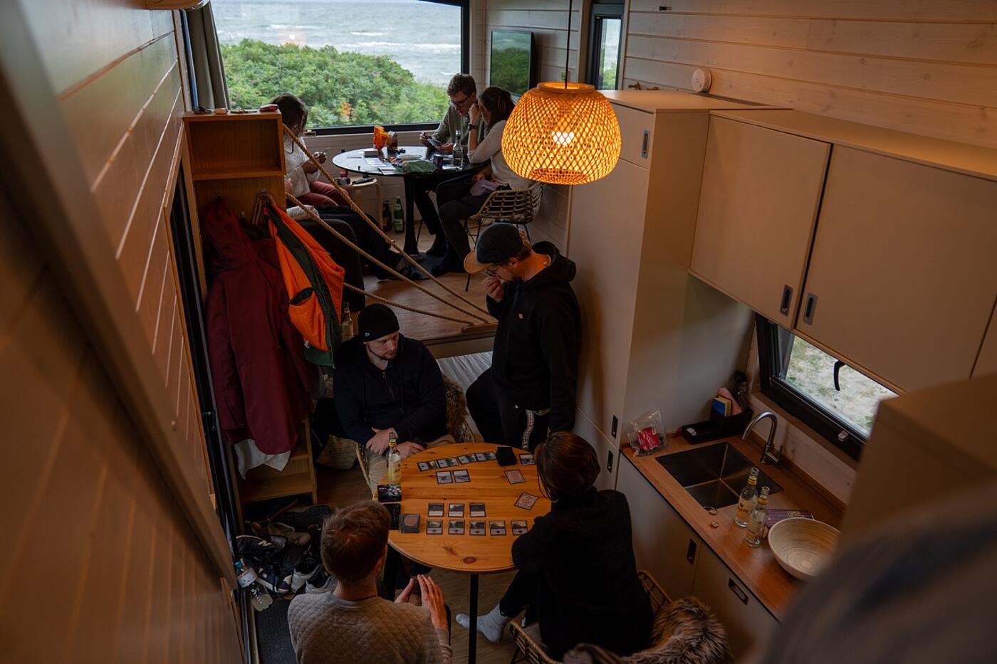 Blick in ein gemütlich beleuchtetes Tiny House, in dem Teammitglieder von visuellverstehen zusammensitzen und sich ruhig beschäftigen.