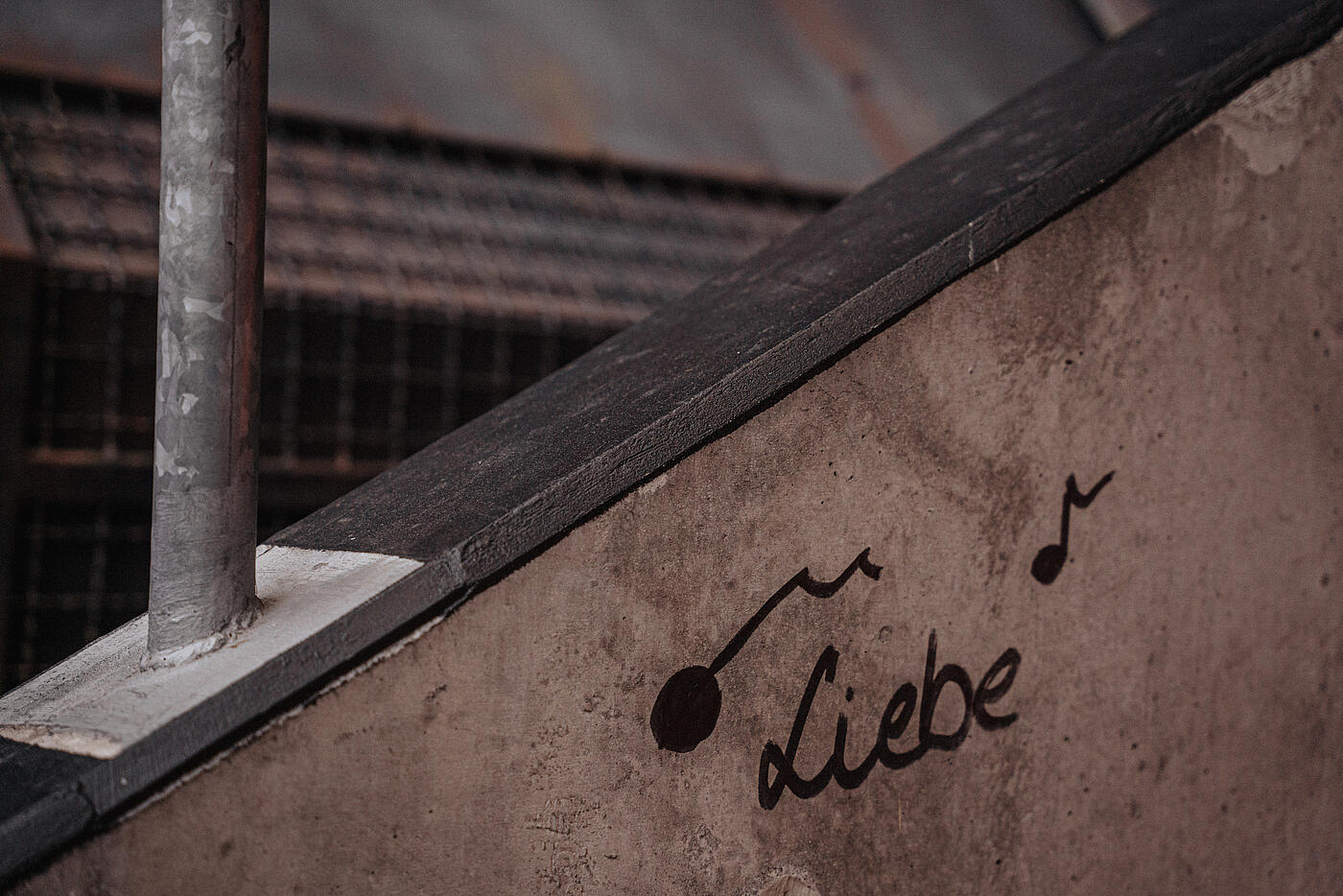 Schriftzug „Liebe“ auf einer verwitterten Mauer. 