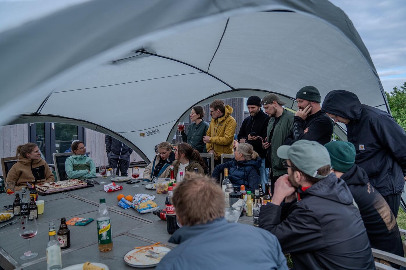 Viele Teammitglieder von visuellverstehen sitzen unter einem Pavillon im Freien und nehmen eine Mahlzeit zu sich.