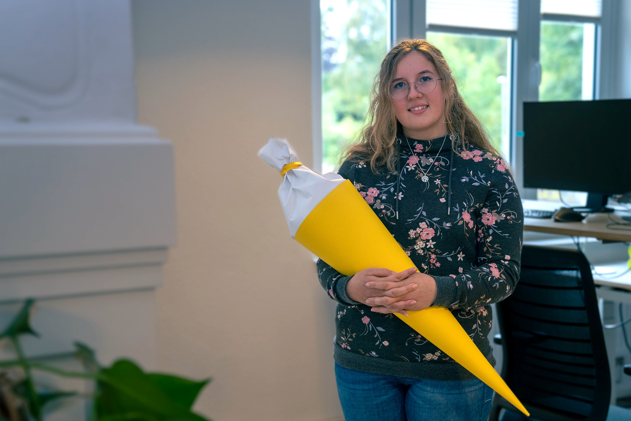 Eine Mitarbeiterin von visuellverstehen hält eine große gelbe Schultüte in der Hand.