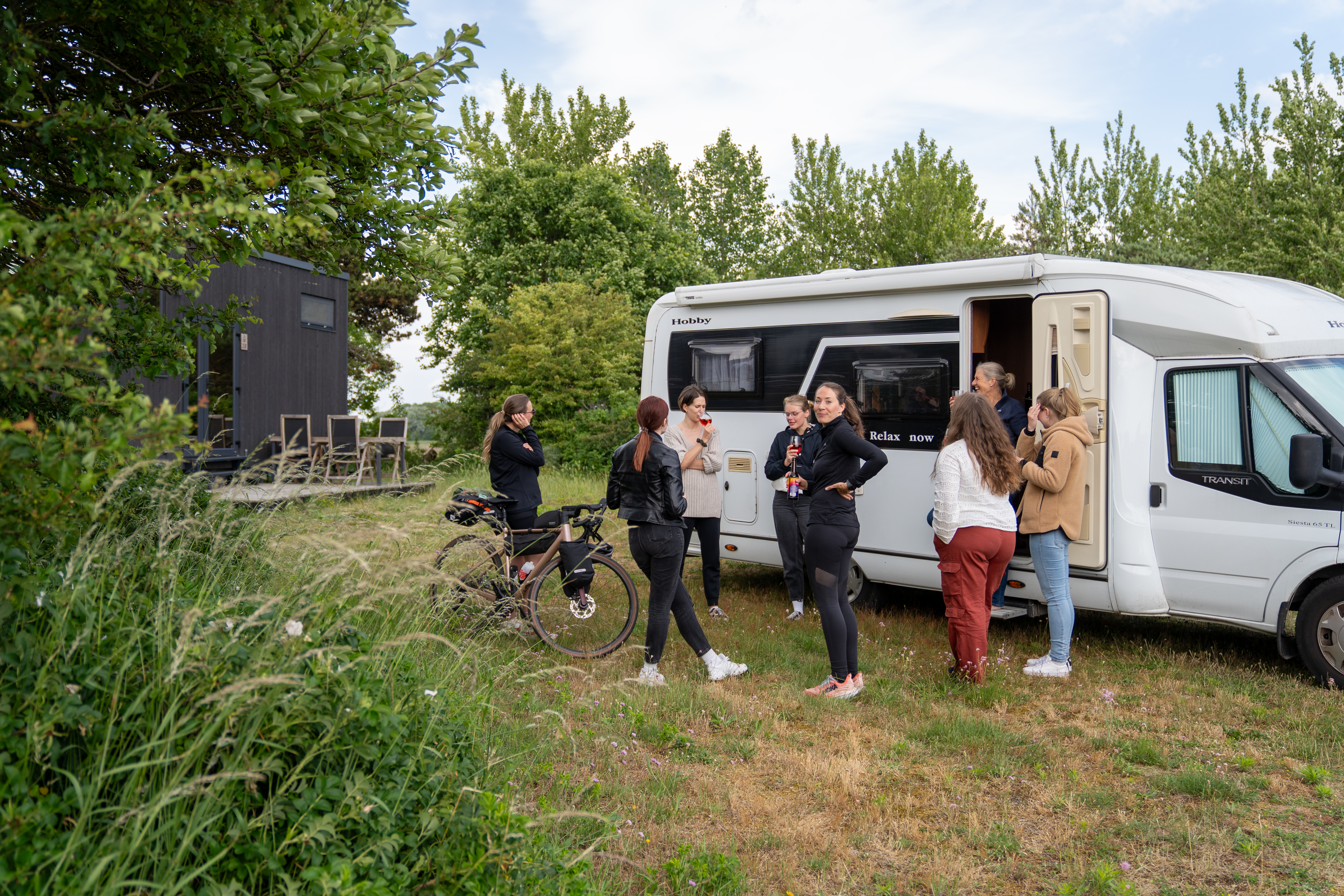 Mehrere Teammitglieder von visuellverstehen stehen vor einem Wohnmobil im Grünen und unterhalten sich.