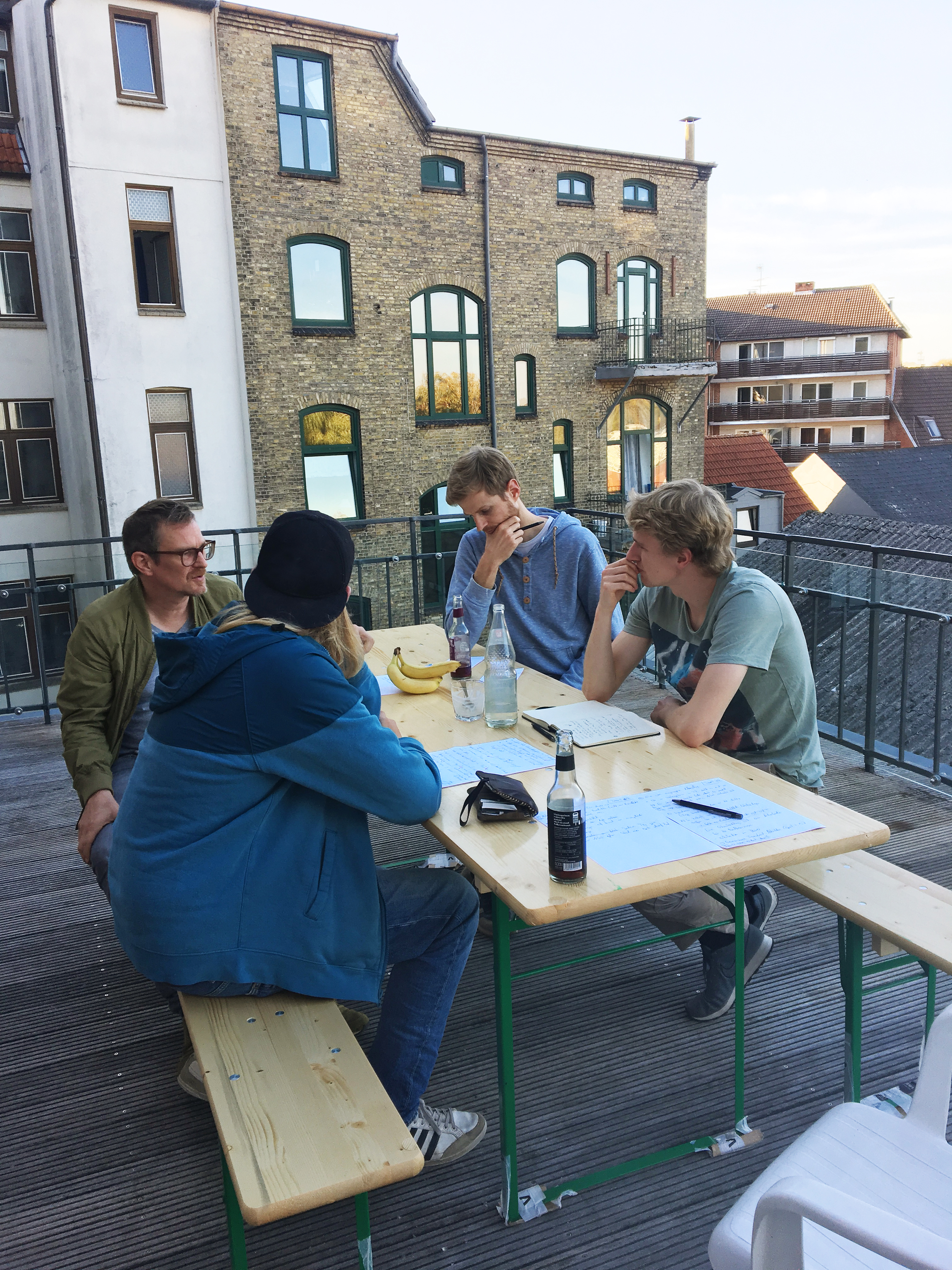 Bei der Klausurtagung 2018 sitzen Teammitglieder draußen an einem Tisch und arbeiten.